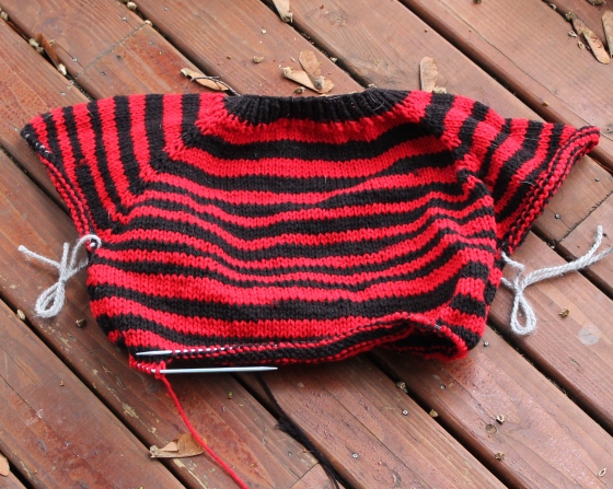 Halfway done knit red and black striped sweater